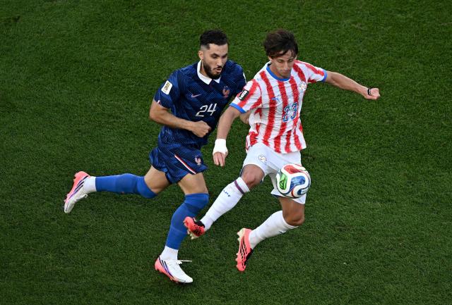 France's forward #24 Rayan Cherki and Paraguay's midfielder #23 Matias Galarza fight for the ball during the 2026 World Cup round of 16 football match between Paraguay and France at the Philadelphia Stadium in Philadelphia on July 4, 2026.  (Photo by Jewel SAMAD / AFP)