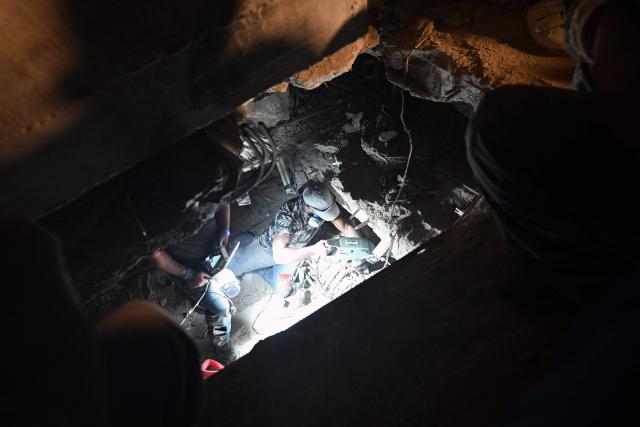 A rescuer works inside a cavity amid the rubble of the OPPE buildings, a residential complex heavily damaged by the earthquakes, in Caraballeda, La Guaira state, Venezuela, on July 4, 2026, after twin earthquakes. Venezuela's devastating twin earthquakes have killed nearly 3,000, official figures showed on July 4, as international rescue teams began winding down search operations for survivors in the rubble. (Photo by Juan BARRETO / AFP)