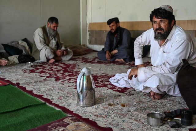 This photograph taken on June 18, 2026 shows Afghan traders sitting inside their office at a container yard in the Spin Boldak district of Afghanistan's Kandahar province. In Afghanistan's southern Kandahar province, a once thriving business of trading car parts from far-flung places has crashed to a halt due to conflicts at the country's borders. (Photo by Sanaullah SEIAM / AFP)