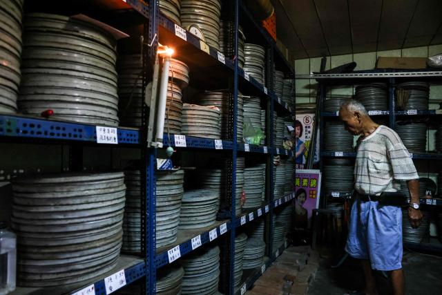 Film projectionist and collector Wang Chin-ting looks through shelves of film canisters at his private archive at his house in Changhua County on May 29, 2026. In a dimly lit red-brick house in central Taiwan, film hunter Wang Wei and his team haul out ageing film reels, salvaging the fragile remnants of a cinema boom that nearly vanished from history. (Photo by I-Hwa Cheng / AFP) / TO GO WITH: Taiwan-culture-history-language, FEATURE by Joy CHIANG