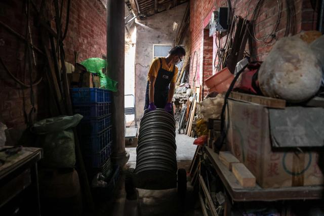 A staff member from the Taiwan Film and Audiovisual Institute transports a stack of Taiwanese-language film reels from a private archive in Changhua County on May 29, 2026. In a dimly lit red-brick house in central Taiwan, film hunter Wang Wei and his team haul out ageing film reels, salvaging the fragile remnants of a cinema boom that nearly vanished from history. (Photo by I-Hwa Cheng / AFP) / TO GO WITH: Taiwan-culture-history-language, FEATURE by Joy CHIANG
