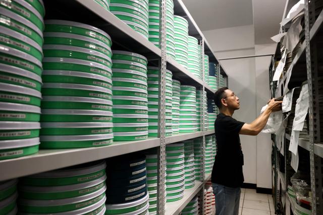 Lin Chia-hao of the Taiwan Film and Audiovisual Institute (TFAI) searches through shelves of archived film reels at the institute in New Taipei City on June 23, 2026. In a dimly lit red-brick house in central Taiwan, film hunter Wang Wei and his team haul out ageing film reels, salvaging the fragile remnants of a cinema boom that nearly vanished from history. (Photo by I-Hwa Cheng / AFP) / TO GO WITH: Taiwan-culture-history-language, FEATURE by Joy CHIANG