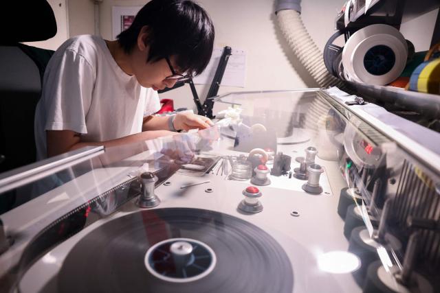 A technician at Preservation and Restoration Center repairs a Taiwanese-language film at the Taiwan Film and Audiovisual Institute in New Taipei City on June 23, 2026. In a dimly lit red-brick house in central Taiwan, film hunter Wang Wei and his team haul out ageing film reels, salvaging the fragile remnants of a cinema boom that nearly vanished from history. (Photo by I-Hwa Cheng / AFP) / TO GO WITH: Taiwan-culture-history-language, FEATURE by Joy CHIANG