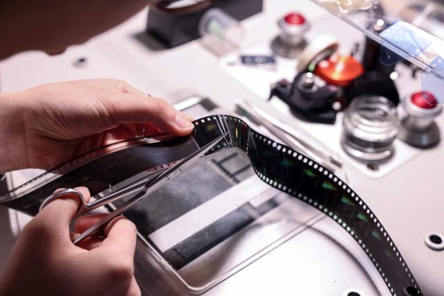 A technician at Preservation and Restoration Center repairs a Taiwanese-language film at the Taiwan Film and Audiovisual Institute in New Taipei City on June 23, 2026. In a dimly lit red-brick house in central Taiwan, film hunter Wang Wei and his team haul out ageing film reels, salvaging the fragile remnants of a cinema boom that nearly vanished from history. (Photo by I-Hwa Cheng / AFP) / TO GO WITH: Taiwan-culture-history-language, FEATURE by Joy CHIANG