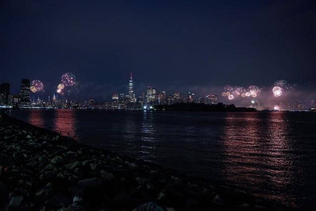 Fireworks illuminate the Manhattan skyline during the Macy's Fourth of July Fireworks celebration in New York City, as the Empire State Building is lit in red, white and blue, as seen from Liberty State Park in Jersey City, New Jersey, on July 4, 2026. (Photo by kena betancur / AFP)