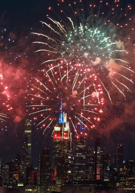 Fireworks illuminate the Manhattan skyline during the Macy's Fourth of July Fireworks celebration in New York City, as the Empire State Building is lit in red, white and blue, as seen from Liberty State Park in Jersey City, New Jersey, on July 4, 2026. (Photo by kena betancur / AFP)
