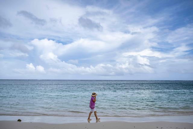 A woman walks along a beach as the forecasted Super Typhoon Bavi approaches in Guam, Northern Mariana Islands, on July 5, 2026. (Photo by Yuichi YAMAZAKI / AFP)
