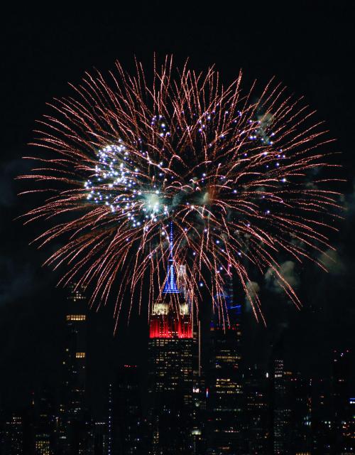 Fireworks illuminate the Manhattan skyline during the Macy's Fourth of July Fireworks celebration in New York City, as the Empire State Building is lit in red, white and blue, as seen from Liberty State Park in Jersey City, New Jersey, on July 4, 2026. (Photo by kena betancur / AFP)