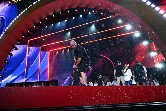Workers push water off the stage before US President Donald Trump speaks during the "Salute to America" Independence Day celebration on the National Mall in Washington, DC, on July 4, 2026. The nation is marking the 250th anniversary of the United States Declaration of Indpendence. (Photo by Kent NISHIMURA / AFP)