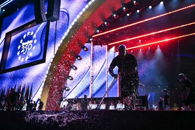 Workers push water off the stage before US President Donald Trump speaks during the "Salute to America" Independence Day celebration on the National Mall in Washington, DC, on July 4, 2026. The nation is marking the 250th anniversary of the United States Declaration of Indpendence. (Photo by Kent NISHIMURA / AFP)