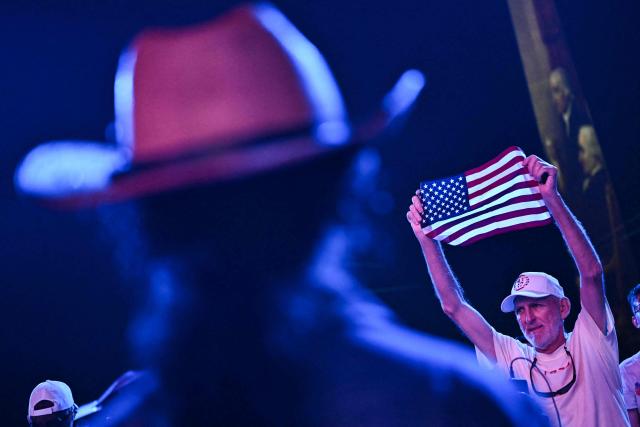 An attendee holds up an American flag as he waits for US President Donald Trump to speak during the "Salute to America" Independence Day celebration on the National Mall in Washington, DC, on July 4, 2026. The nation is marking the 250th anniversary of the United States Declaration of Indpendence. (Photo by Kent NISHIMURA / AFP)