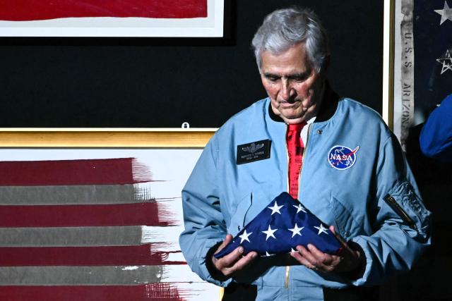 Retired astronaut Harrison Schmitt holds an American flag as he stands onstage as US President Donald Trump speaks during the "Salute to America" Independence Day celebration on the National Mall in Washington, DC, on July 4, 2026. The nation is marking the 250th anniversary of the United States Declaration of Indpendence. (Photo by Kent NISHIMURA / AFP)