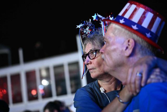 Two attendees watch fireworks during the "Salute to America" Independence Day celebration on the National Mall in Washington, DC, in the early morning hours of July 5, 2026. The nation is marking the 250th anniversary of the United States Declaration of Indpendence. (Photo by Kent NISHIMURA / AFP)