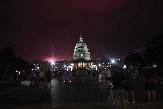People watch fireworks during the "Salute to America" Independence Day celebration on the National Mall in Washington, DC, in the early morning hours of July 5, 2026. The nation is marking the 250th anniversary of the United States Declaration of Indpendence. (Photo by Matthew Hatcher / AFP)