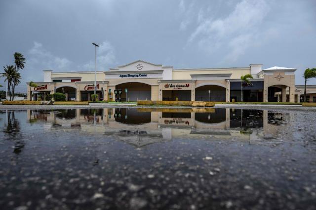 A empty parking lot is seen at a shopping center as the forecasted Super Typhoon Bavi approaches in Guam, Northern Mariana Islands, on July 5, 2026. People in Guam and the Northern Marianas moved to emergency evacuation centers and made last-minute preparations on July 5, hours before a "super typhoon" was projected to bulldoze through the US Pacific territories. (Photo by Yuichi YAMAZAKI / AFP)