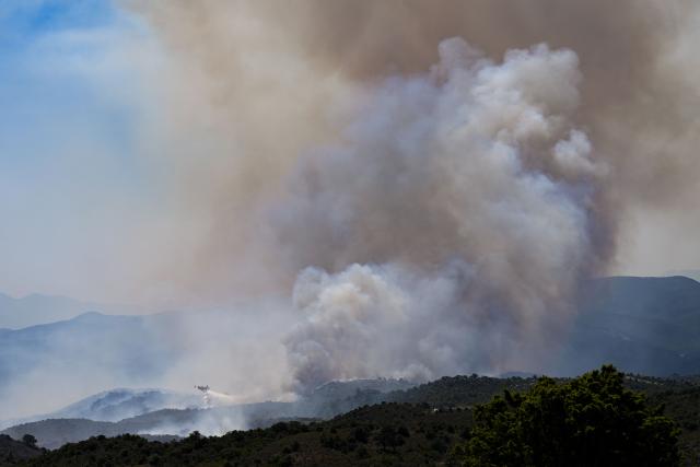 A Canadair CL-415 plane of France's Civil Security services drops water on a wildfire at the Col des Auzines, near Trevillach, southern France, on July 5, 2026. A wildfire broke out on July 4 at around 19h30 (1730 GMT) in a hard-to-reach massif near Trevillach, in the Pyrenees-Orientales department of southern France and spread rapidly overnight, burning through nearly 1,000 hectares by the morning of July 5, but the fire is no longer spreading freely, according to the prefecture. More than 580 firefighters have been deployed on the ground to fight the blaze. (Photo by Matthieu RONDEL / AFP)