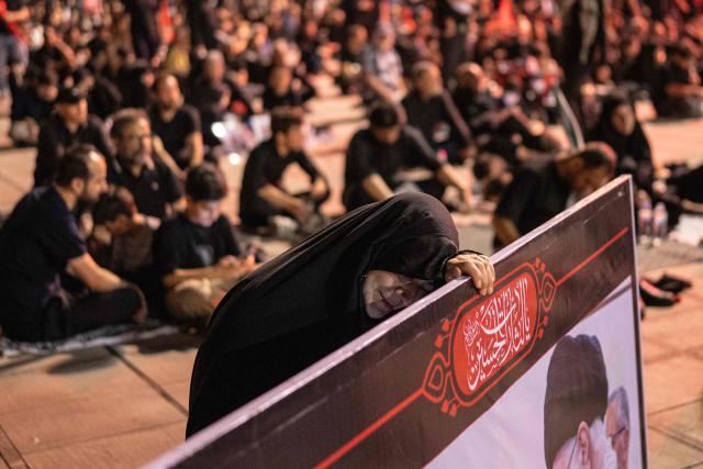 A woman reacts behind a banner as people gather to mourn Iran's slain supreme leader Ayatollah Ali Khamenei during the funeral ceremonies at the Grand Mosalla in Tehran on July 5, 2026. Iranian leaders on July 5 joined prayers over the casket of late supreme leader Ali Khamenei during a second day of funeral ceremonies, which was declared a public holiday across Iran. Khamenei's body will be moved out of the Grand Mosalla later in the day, where it is lying in state, as part of preparations for processions through the capital the following day. (Photo by AFP) / 