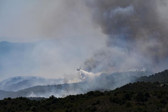 A Canadair CL-415 plane of France's Civil Security services drops water on a wildfire at the Col des Auzines, near Trevillach, southern France, on July 5, 2026. A wildfire broke out on July 4 at around 19h30 (1730 GMT) in a hard-to-reach massif near Trevillach, in the Pyrenees-Orientales department of southern France and spread rapidly overnight, burning through nearly 1,000 hectares by the morning of July 5, but the fire is no longer spreading freely, according to the prefecture. More than 580 firefighters have been deployed on the ground to fight the blaze. (Photo by Matthieu RONDEL / AFP)