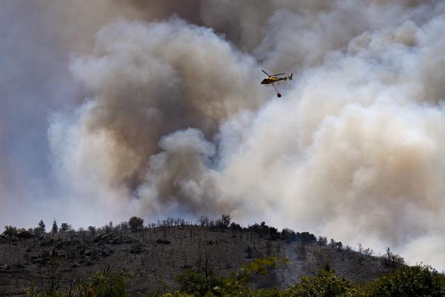 The SDIS11 (Service départemental d'incendie et de secours) firefighting helicopter H125 drops water on a wildfire near the Col des Auzines, near Trevillach, southern France, on July 5, 2026. A wildfire broke out on July 4 at around 19h30 (1730 GMT) in a hard-to-reach massif near Trevillach, in the Pyrenees-Orientales department of southern France and spread rapidly overnight, burning through nearly 1,000 hectares by the morning of July 5, but the fire is no longer spreading freely, according to the prefecture. More than 580 firefighters have been deployed on the ground to fight the blaze. (Photo by Matthieu RONDEL / AFP)