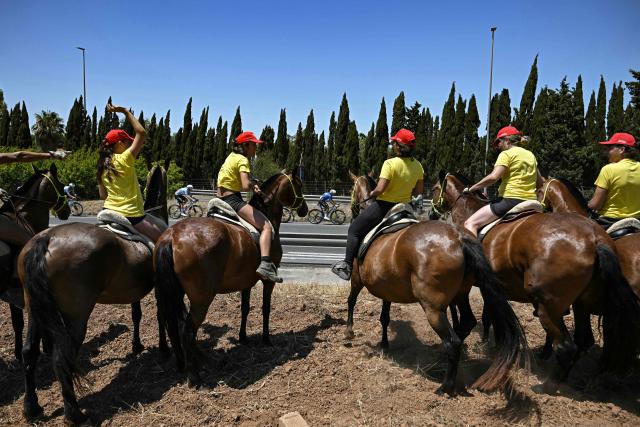 The pack of riders (peloton) cycles past spectators on horseback along the race route during the 2nd stage of the 113th edition of the Tour de France cycling race, 168,5 km between Tarragona and Barcelona in northeastern Spain, on July 5, 2026. (Photo by Loic VENANCE / AFP)