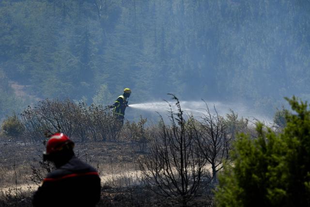 A French firefighter sprays water to extinguish a forest fire near Trevillach, southern France, on July 5, 2026. A wildfire broke out on July 4 at around 19h30 (1730 GMT) in a hard-to-reach massif near Trevillach, in the Pyrenees-Orientales department of southern France and spread rapidly overnight, burning through nearly 1,000 hectares by the morning of July 5, but the fire is no longer spreading freely, according to the prefecture. More than 580 firefighters have been deployed on the ground to fight the blaze. (Photo by Matthieu RONDEL / AFP)