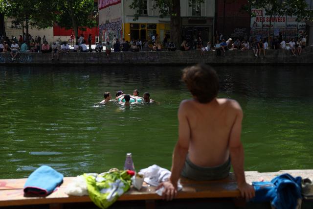 Youths cool down along the Canal Saint-Martin in Paris on July 5, 2026.  (Photo by ROMAIN PERROCHEAU / AFP)