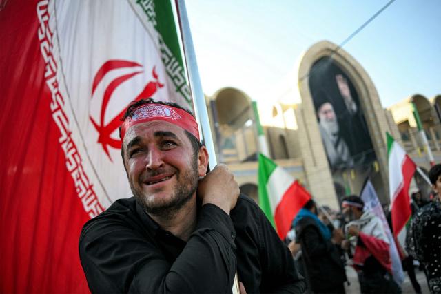 A man reacts as he and others gather to mourn Iran's slain supreme leader Ayatollah Ali Khamenei during the funeral ceremonies at the Grand Mosalla in Tehran on July 5, 2026. Iranian leaders on July 5 joined prayers over the casket of late supreme leader Ali Khamenei during a second day of funeral ceremonies, which was declared a public holiday across Iran. Khamenei's body will be moved out of the Grand Mosalla later in the day, where it is lying in state, as part of preparations for processions through the capital the following day. (Photo by Ozan KOSE / AFP) / 