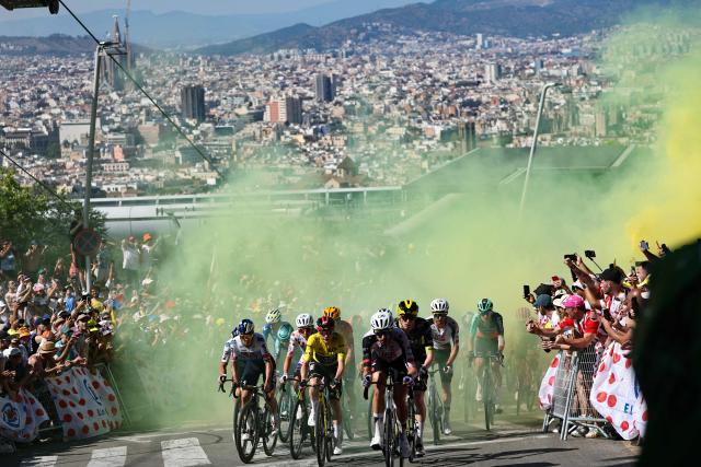 UAE Team Emirates - XRG's Slovenian rider Tadej Pogacar wearing the climber's dotted jersey and Team Visma | Lease a Bike's Danish rider Jonas Vingegaard wearing the overall leader's yellow jersey and riders emerge from yellow smoke as they cycle in the Montjuic Palace ascent in the final kilometers of the 2nd stage of the 113th edition of the Tour de France cycling race, 168,5 km between Tarragona and Barcelona in northeastern Spain, on July 5, 2026. (Photo by Anne-Christine POUJOULAT / AFP)