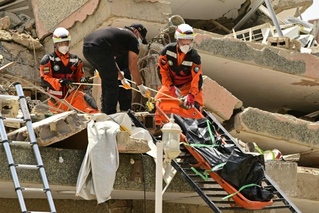 EDITORS NOTE: Graphic content / Rescue workers recover a corpse from the rubble in Playa Grande, Catia La Mar, La Guaira State, Venezuela on July 5, 2026, following the June 24 twin earthquakes. The devastating earthquakes that struck Venezuela eleven days ago have now claimed nearly 3,000 lives, according to the latest figures released on July 4, 2026, as foreign rescue teams wind down their operations to find survivors. (Photo by MARTIN BERNETTI / AFP)