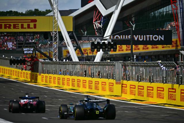 Ferrari's Monegasque driver Charles Leclerc (L) takes the chequered flag to win the Formula One British Grand Prix at the Silverstone motor racing circuit in Silverstone, central England, on July 5, 2026. (Photo by Ben STANSALL / AFP)