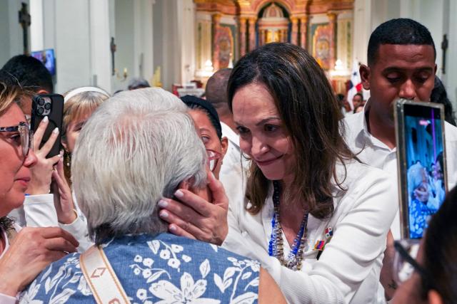 Venezuelan opposition leader Maria Corina Machado holds a woman's face as she leaves after a mass at the National Basilica Santa Maria la Antigua in Panama City on July 5, 2026. (Photo by ARNULFO FRANCO / AFP)