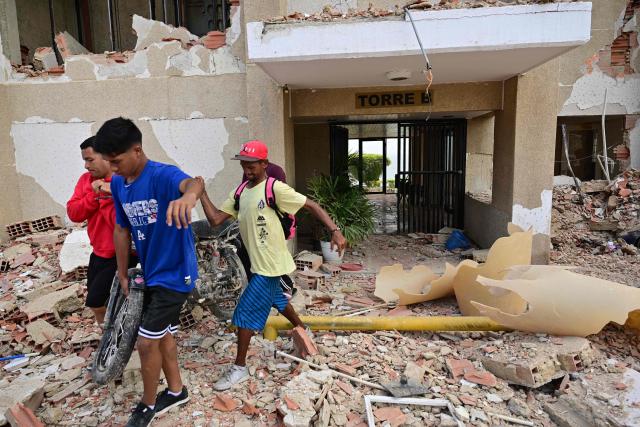 Volunteers carry a motorcycle from a destroyed building in Playa Grande, Catia La Mar, La Guaira State, Venezuela on July 5, 2026, following the June 24 twin earthquakes. The devastating earthquakes that struck Venezuela eleven days ago have now claimed nearly 3,000 lives, according to the latest figures released on July 4, 2026, as foreign rescue teams wind down their operations to find survivors. (Photo by MARTIN BERNETTI / AFP)