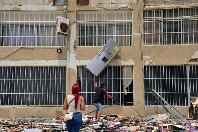 A refrigerator is lowered through a window from a damaged building in Playa Grande, Catia La Mar, La Guaira State, Venezuela on July 5, 2026, following the June 24 twin earthquakes. The devastating earthquakes that struck Venezuela eleven days ago have now claimed nearly 3,000 lives, according to the latest figures released on July 4, 2026, as foreign rescue teams wind down their operations to find survivors. (Photo by MARTIN BERNETTI / AFP)