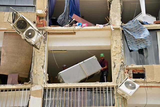 Men prepare to lower a refrigerator through a window of a damaged building in Playa Grande, Catia La Mar, La Guaira State, Venezuela on July 5, 2026, following the June 24 twin earthquakes. The devastating earthquakes that struck Venezuela eleven days ago have now claimed nearly 3,000 lives, according to the latest figures released on July 4, 2026, as foreign rescue teams wind down their operations to find survivors. (Photo by MARTIN BERNETTI / AFP)