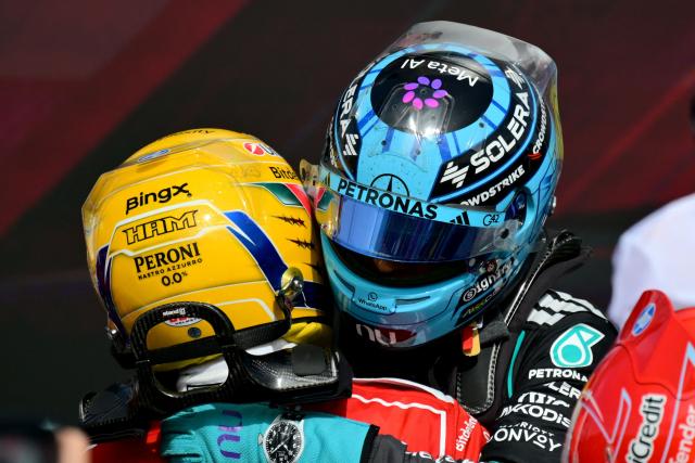 Third-placed Ferrari's British driver Lewis Hamilton (L) hugs second-placed Mercedes' British driver George Russell (R) at the end of the Formula One British Grand Prix at the Silverstone motor racing circuit in Silverstone, central England, on July 5, 2026. (Photo by Andrej ISAKOVIC / AFP)
