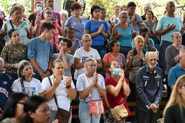 People attend a mass at the Jerusalem square in Maiquetia, Venezuela on July 5, 2026, following the June 24 twin earthquakes. The devastating earthquakes that struck Venezuela eleven days ago have now claimed nearly 3,000 lives, according to the latest figures released on July 4, 2026, as foreign rescue teams wind down their operations to find survivors. (Photo by Raul ARBOLEDA / AFP)