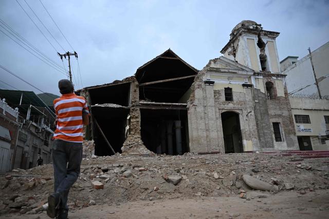 A man looks at the destroyed San Sebastian church in Maiquetia, Venezuela on July 5, 2026, following the June 24 twin earthquakes. The devastating earthquakes that struck Venezuela eleven days ago have now claimed nearly 3,000 lives, according to the latest figures released on July 4, 2026, as foreign rescue teams wind down their operations to find survivors. (Photo by Raul ARBOLEDA / AFP)
