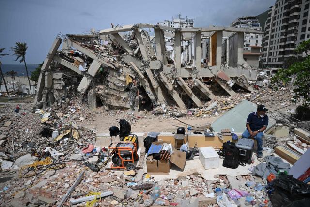 EDITORS NOTE: Graphic content / A man sits near a destroyed building in Macuto, Vargas state, Venezuela, on July 5, 2026, following the June 24 twin earthquakes. The devastating earthquakes that struck Venezuela eleven days ago have now claimed nearly 3,000 lives, according to the latest figures released on July 4, 2026, as foreign rescue teams wind down their operations to find survivors. (Photo by Raul ARBOLEDA / AFP)