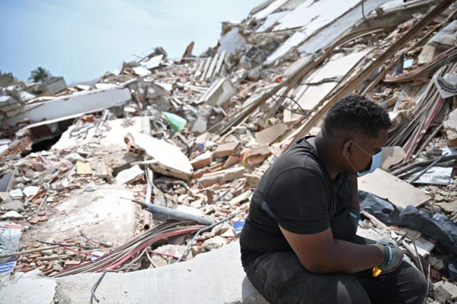 EDITORS NOTE: Graphic content / A man sits next to rubble in Macuto, Vargas state, Venezuela, on July 5, 2026, following the June 24 twin earthquakes. The devastating earthquakes that struck Venezuela eleven days ago have now claimed nearly 3,000 lives, according to the latest figures released on July 4, 2026, as foreign rescue teams wind down their operations to find survivors. (Photo by Raul ARBOLEDA / AFP)