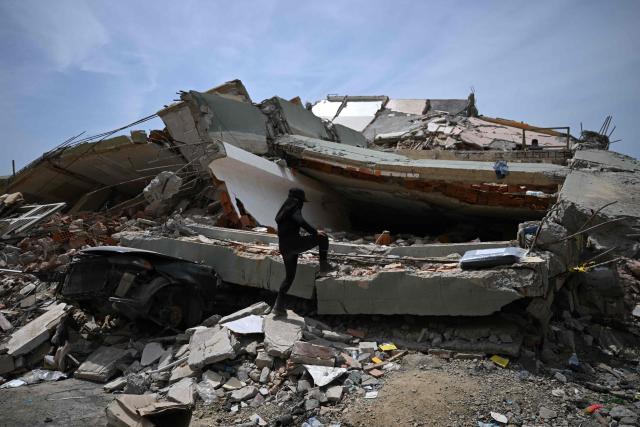 EDITORS NOTE: Graphic content / A person climbs rubble in Macuto, Vargas state, Venezuela, on July 5, 2026, following the June 24 twin earthquakes. The devastating earthquakes that struck Venezuela eleven days ago have now claimed nearly 3,000 lives, according to the latest figures released on July 4, 2026, as foreign rescue teams wind down their operations to find survivors. (Photo by Raul ARBOLEDA / AFP)