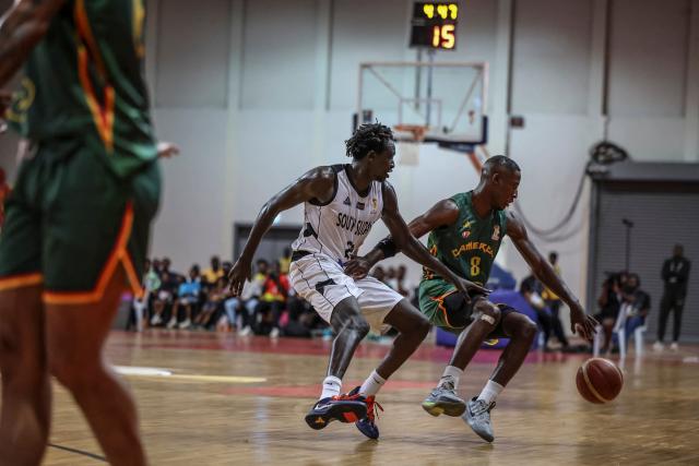 Cameroon's #8 Samir Gbetkom (R) and South Soudan's #20 Jackson Makoi (C) fight for the ball during a basketball match game between Cameron vs South Soudan played on the third day of the African qualifying for the 2027 Men's Basketball World Cup in Qatar, in Douala on July 5, 2026. (Photo by Daniel BELOUMOU OLOMO / AFP)