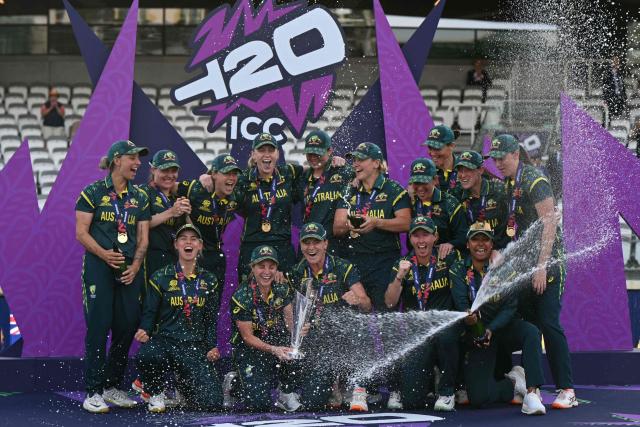 Australia's captain Sophie Molineux holds the trophy as Australia celebrate spraying champagne on the podium after the ICC Women's T20 cricket world cup 2026 final between Australia and England, at Lord's in London on July 5, 2026. Australia thrashed England by seven wickets to win the Women's T20 World Cup final at Lord's on Sunday. Victory gave Australia a record-extending seventh Women's T20 global title as they chased down a target of 151 with 17 balls to spare. (Photo by JUSTIN TALLIS / AFP)