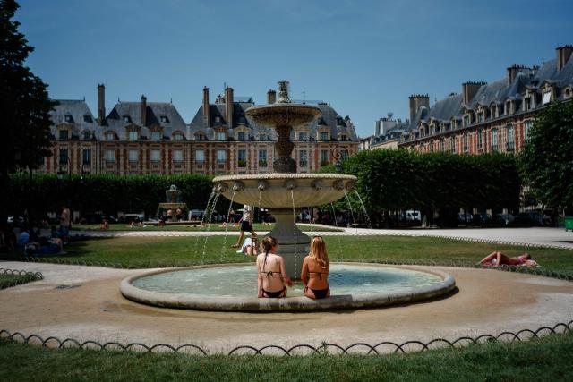 (FILES) Two women cool off in a fountain at Place des Vosges in Paris on June 23, 2026, as France experiences a heatwave. France faces another spell of intense heat, a third spell of intense heat in just over a month, stepping up heat alerts on July 5, 2026 with temperatures beginning to rise again with forecasters predicting it could last until the following weekend. (Photo by Dimitar DILKOFF / AFP)