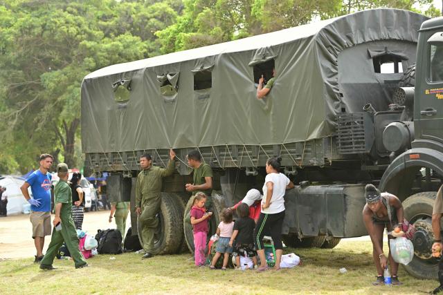 People remain by a military truck at a field hospital and refuge set up in a golf course in Caraballeda, La Guaira state, Venezuela, on July 5, 2026, following the June 24 twin earthquakes. The devastating earthquakes that struck Venezuela eleven days ago have now claimed nearly 3,000 lives, according to the latest figures released on July 4, 2026, as foreign rescue teams wind down their operations to find survivors. (Photo by MARTIN BERNETTI / AFP)