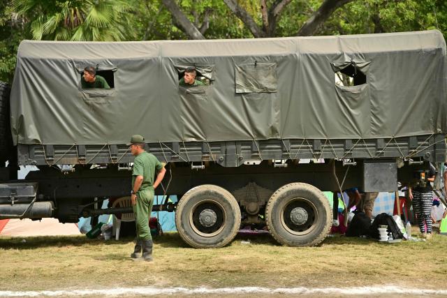 Venezuelan soldiers remain on a military truck at a field hospital and refuge set up in a golf course in Caraballeda, La Guaira state, Venezuela, on July 5, 2026, following the June 24 twin earthquakes. The devastating earthquakes that struck Venezuela eleven days ago have now claimed nearly 3,000 lives, according to the latest figures released on July 4, 2026, as foreign rescue teams wind down their operations to find survivors. (Photo by MARTIN BERNETTI / AFP)