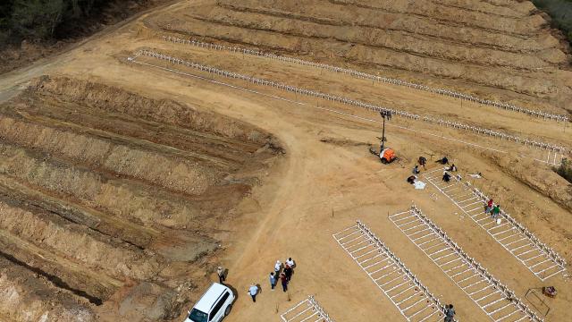 This aerial view shows plots containing the graves of identified (L) and unidentified (R) individuals, victims of the twin earthquakes, at La Esperanza Cemetery in Catia La Mar, La Guaira state, northeast of Caracas, on July 5, 2026. Venezuela's devastating twin earthquakes killed nearly 3,000, updated official figures showed on July 4, as international rescue teams began winding down search operations for survivors in the rubble of the disaster. (Photo by Miguel MEDINA / AFP)
