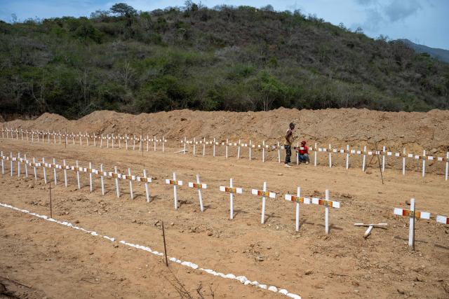 Workers prepare graves for unidentified victims of the June 24 earthquake at La Esperanza Cemetery in Catia La Mar, La Guaira state, northeast of Caracas, on July 5, 2026. Venezuela's devastating twin earthquakes killed nearly 3,000, updated official figures showed on July 4, as international rescue teams began winding down search operations for survivors in the rubble of the disaster. (Photo by Miguel MEDINA / AFP)