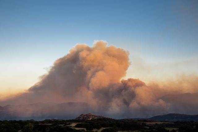 This photograph shows a cloud of smoke from a wildfire burning in the Aspres region seen from Montalba-le-Chateau, in the Pyrenees-Orientales department, southern France on July 5, 2026. A wildfire broke out on July 4 at around 19h30 (1730 GMT) in a hard-to-reach massif near Trevillach, in the Pyrenees-Orientales department of southern France and spread rapidly overnight. More than 10,000 residents are currently being evacuated as the wildfire spreads rapidly, having burned around 2,000 hectares. (Photo by Jc Milhet / AFP)