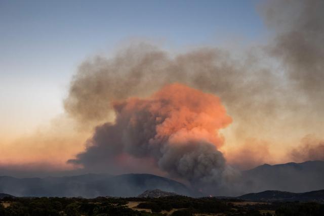 This photograph shows a cloud of smoke from a wildfire burning in the Aspres region seen from Montalba-le-Chateau, in the Pyrenees-Orientales department, southern France on July 5, 2026. A wildfire broke out on July 4 at around 19h30 (1730 GMT) in a hard-to-reach massif near Trevillach, in the Pyrenees-Orientales department of southern France and spread rapidly overnight. More than 10,000 residents are currently being evacuated as the wildfire spreads rapidly, having burned around 2,000 hectares. (Photo by Jc Milhet / AFP)