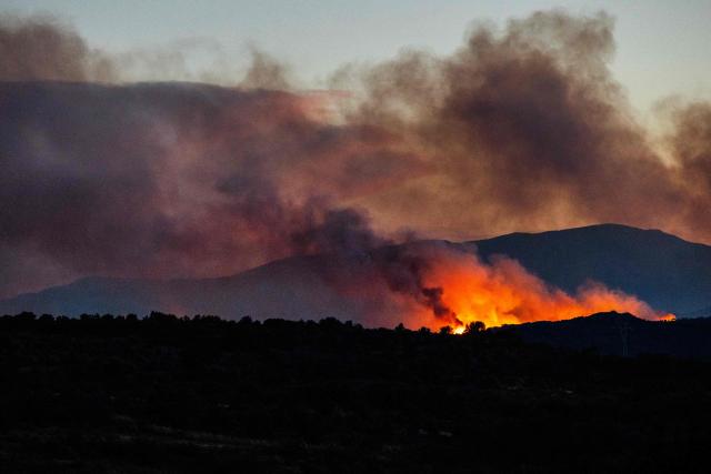 This photograph shows a wildfire burning in the Aspres region seen from Millas, in the Pyrenees-Orientales department, southern France on July 5, 2026. A wildfire broke out on July 4 at around 19h30 (1730 GMT) in a hard-to-reach massif near Trevillach, in the Pyrenees-Orientales department of southern France and spread rapidly overnight. More than 10,000 residents are currently being evacuated as the wildfire spreads rapidly, having burned around 2,000 hectares. (Photo by Jc Milhet / AFP)